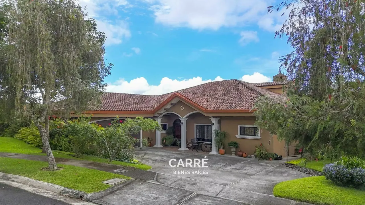 Casa de un nivel rodeada de jardines, en condominio.